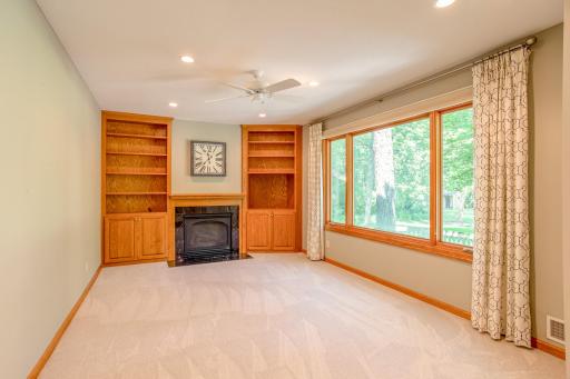 Comfortable family room featuring a cozy fireplace, custom built-in shelving, and oversized windows overlooking the picturesque backyard.