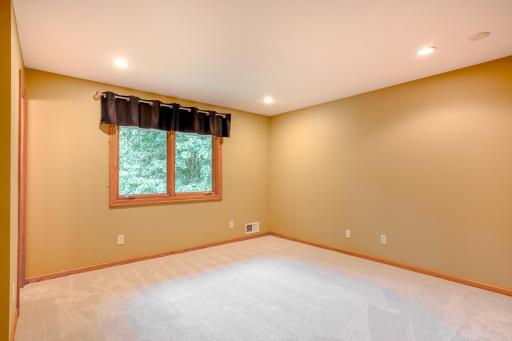 Comfortable secondary bedroom featuring plush carpeting, recessed lighting, and a large window overlooking the surrounding greenery.