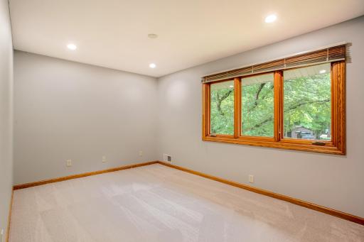 Bright 3rd bedroom with large windows framing peaceful wooded views and filling the room with natural light.
