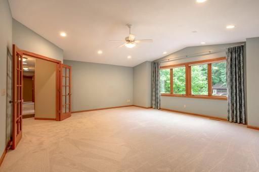 Bright and versatile bonus room featuring recessed lighting, soaring ceilings, and peaceful wooded views, offering endless possibilities for flexible living.