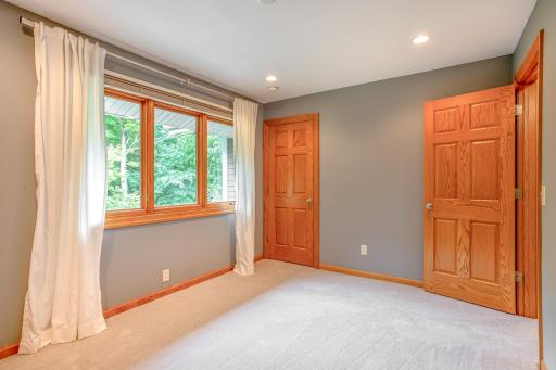 Bright and inviting bedroom featuring a large window with peaceful wooded views, recessed lighting, and neutral finishes that create a comfortable retreat.
