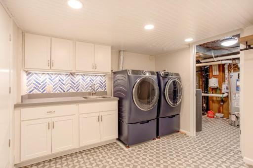 Updated laundry area with abundant cabinetry, utility sink, and stylish backsplash combines everyday convenience with attractive design.