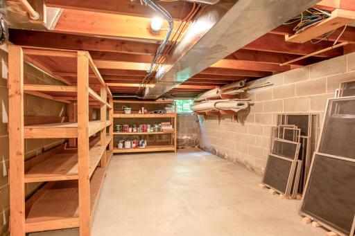 Expansive unfinished storage room with shelving provides exceptional space for seasonal items, tools, and household organization.