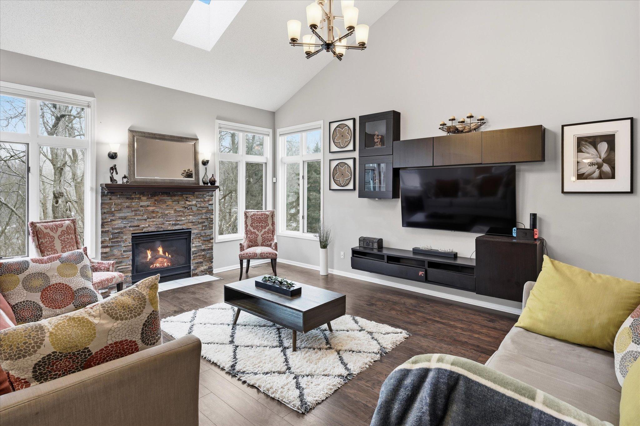 A stunning space for entertaining or relaxing, featuring high ceilings, neutral tones, and a fireplace as the centerpiece