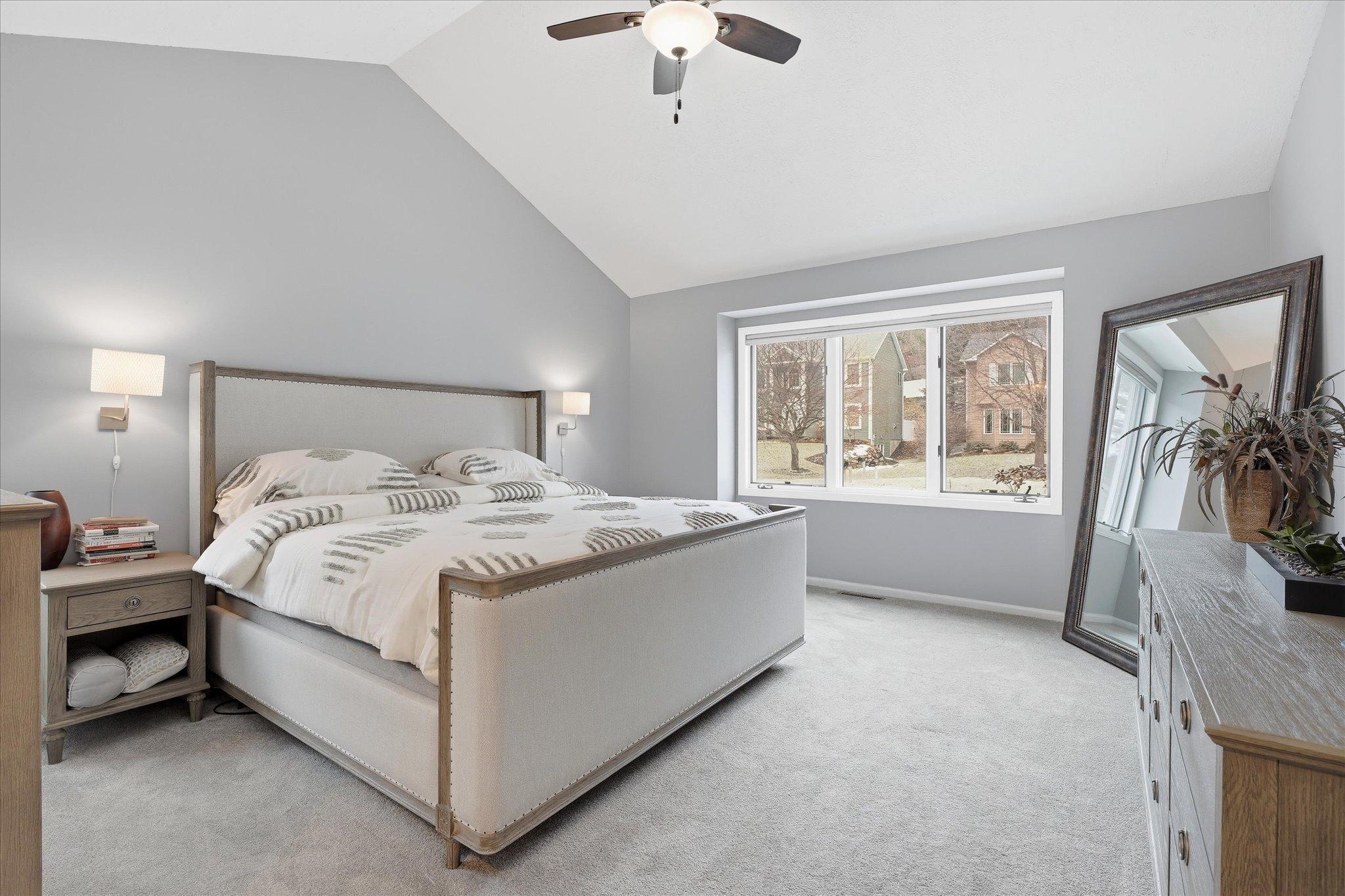 Spacious owner’s suite with vaulted ceilings, a large window bringing in natural light, neutral colors, and a generous walk-in closet.