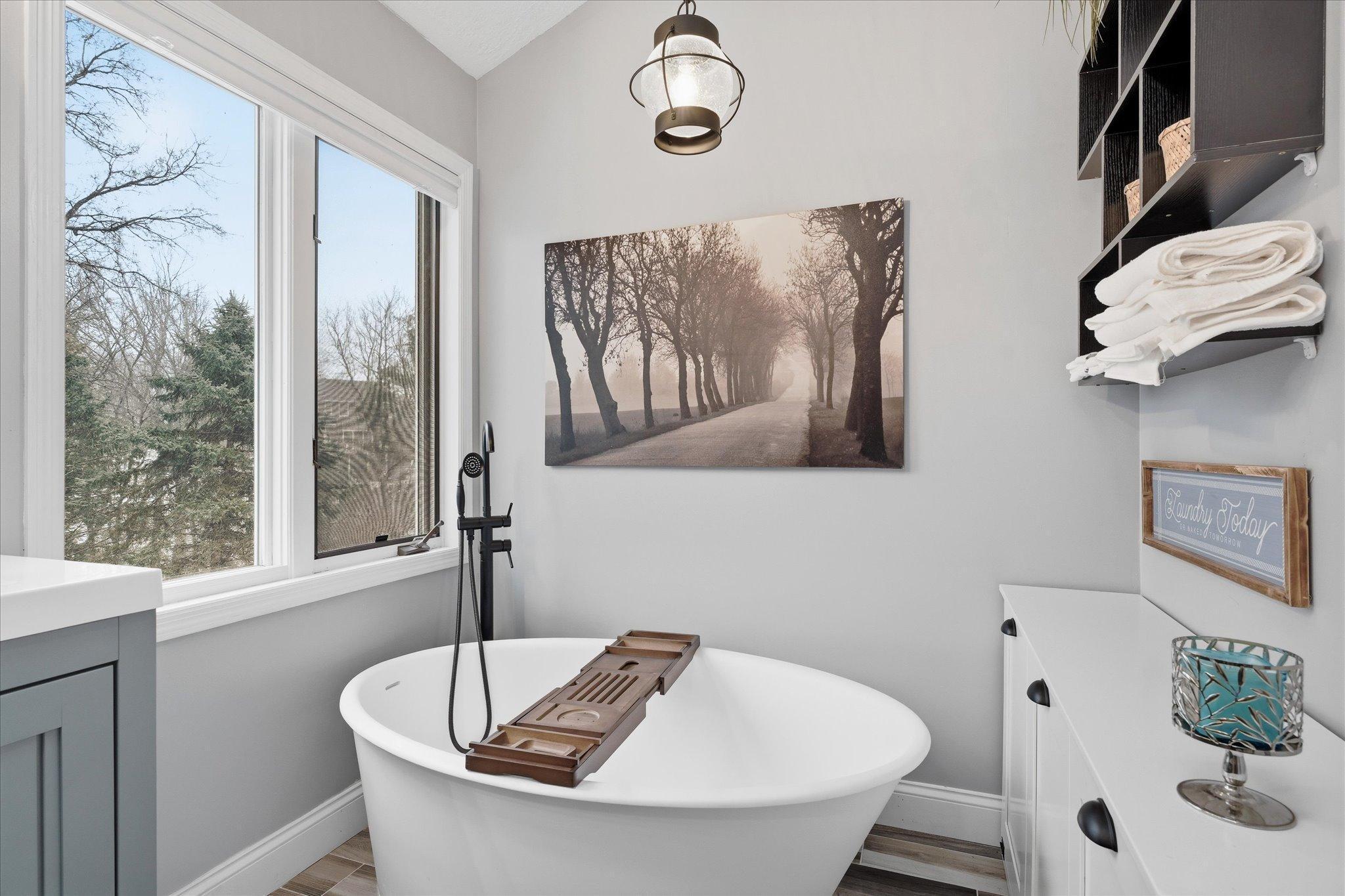 Luxurious owner’s bath with heated tile floors, a free-standing soaking tub, tile shower, double vanity, and soaring ceilings