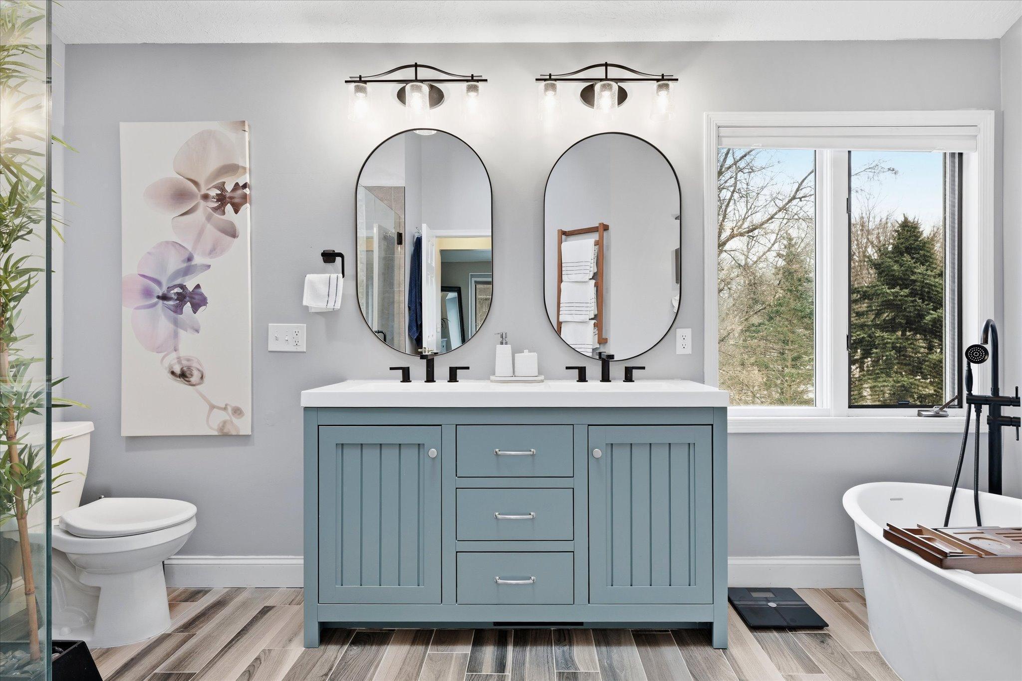 Spa-inspired owner’s bath featuring heated tile floors, a freestanding tub, tile shower, dual vanities, and a bright, open feel with vaulted ceilings.
