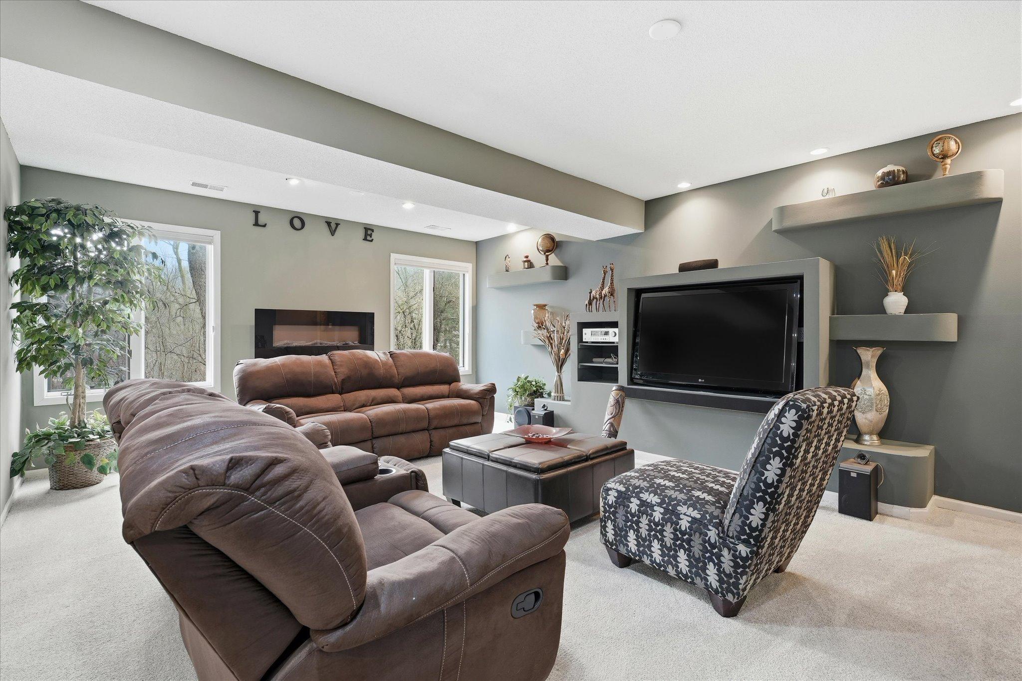 Cozy lower-level family room with large windows, an electric fireplace, and plenty of space to relax or enjoy movie nights with family and friends.