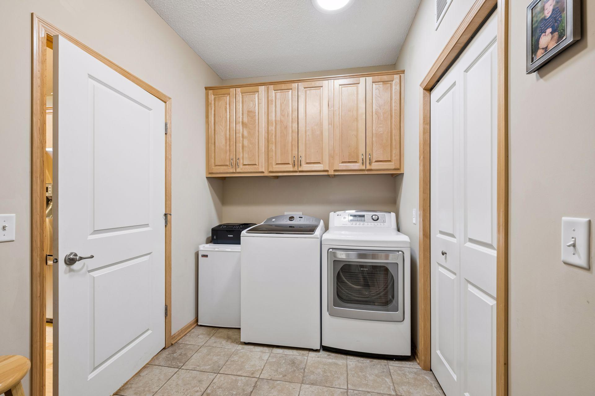 Spacious laundry/mud room offers extra cabinetry + hanging storage and ceramic tile floors.