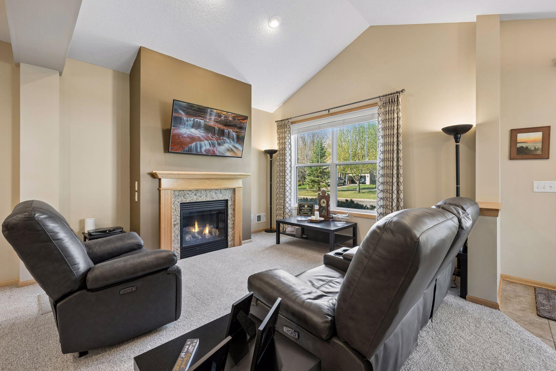 Vaulted and bright living room features a cozy gas fireplace and windows to the front of the home.