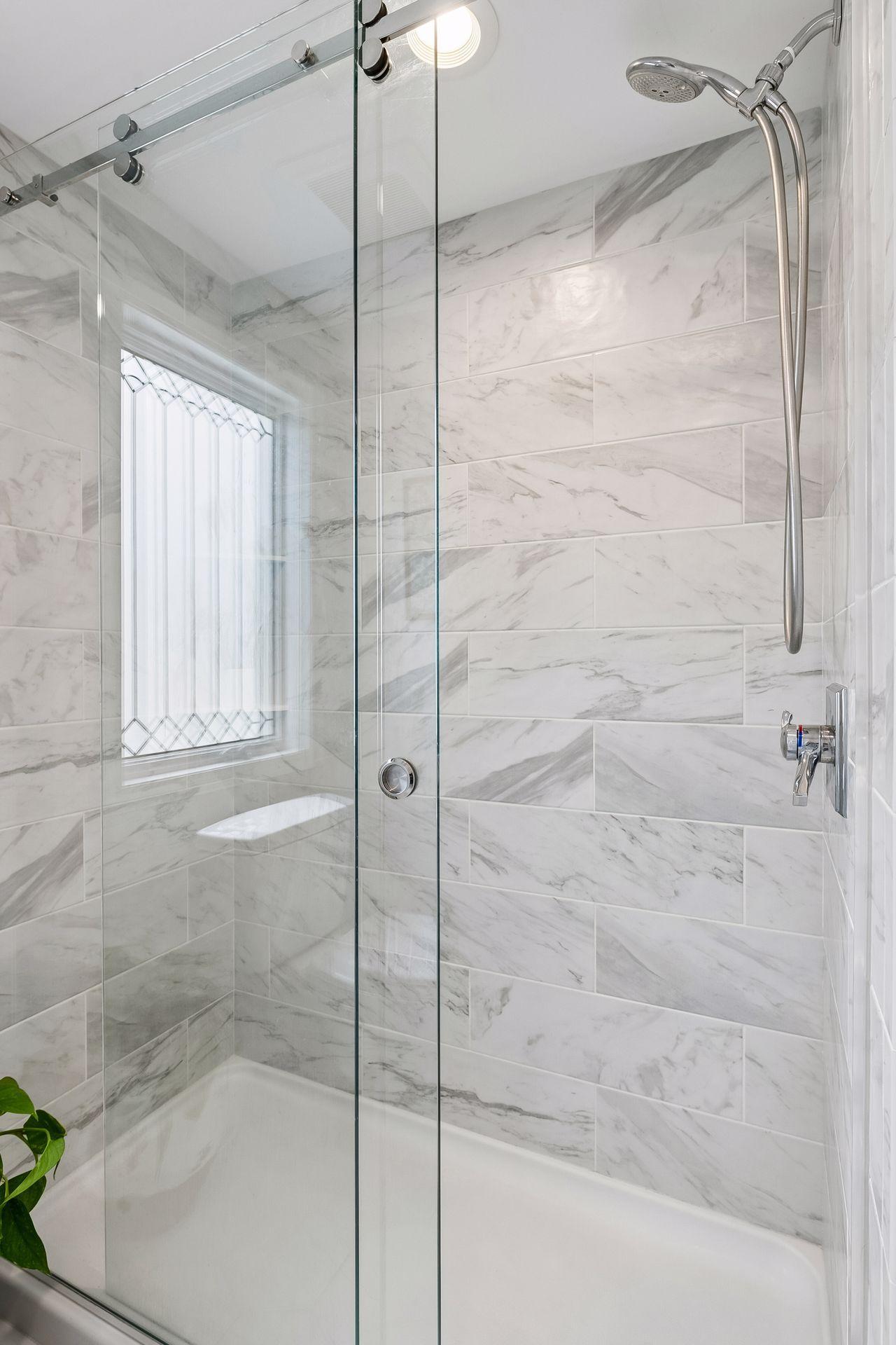 Main floor full bathroom with sliding glass door and tilework on shower.