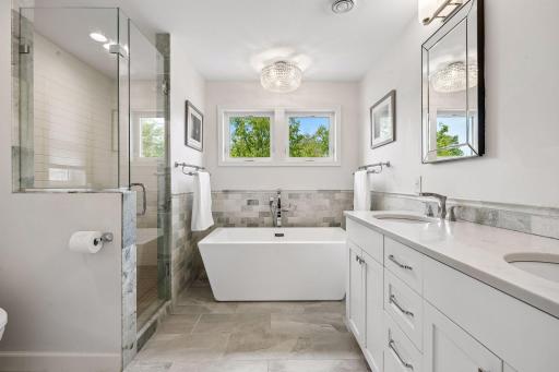 Sumptuous primary bathroom is a welcome respite from the hustle and bustle, with designer soaking tub, dual sinks, beautiful high-end details, and tile/quartz surfaces.
