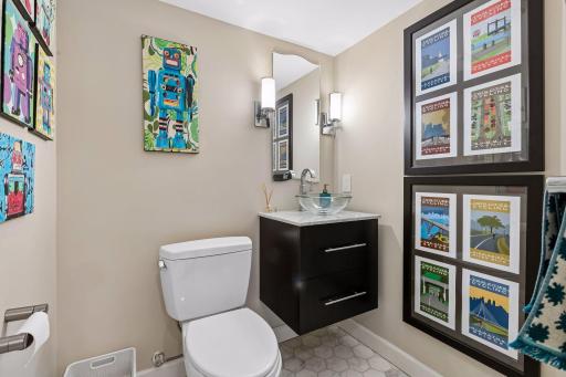 Lower level half bathroom is just off the family room. Fun detailing like floating box vanity, bowl sink and hex tiled floor.