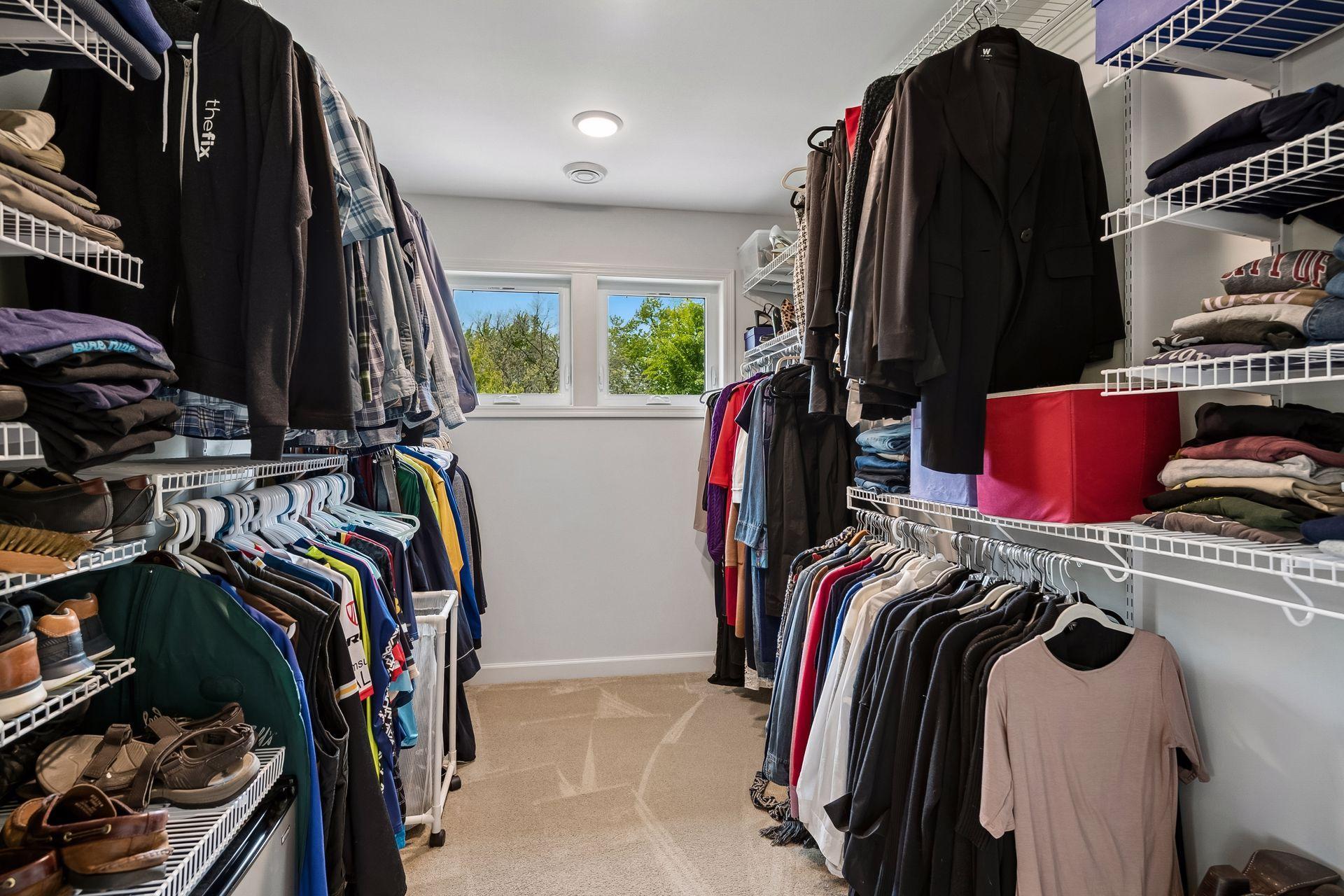 Spacious walk-in closet of primary bedroom, with windows.