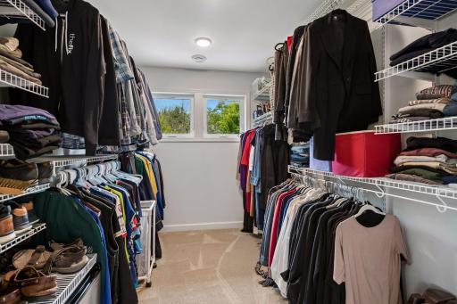 Spacious walk-in closet of primary bedroom, with windows and organizers for everything.