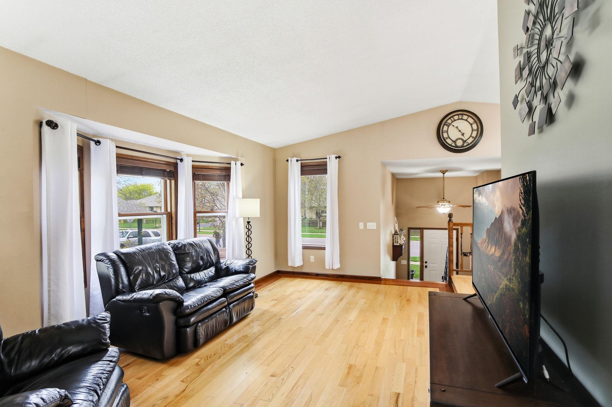 Living room with a bright bay window and vaulted ceiling brings in abundant natural light and adds architectural charm, creating a warm and inviting space.