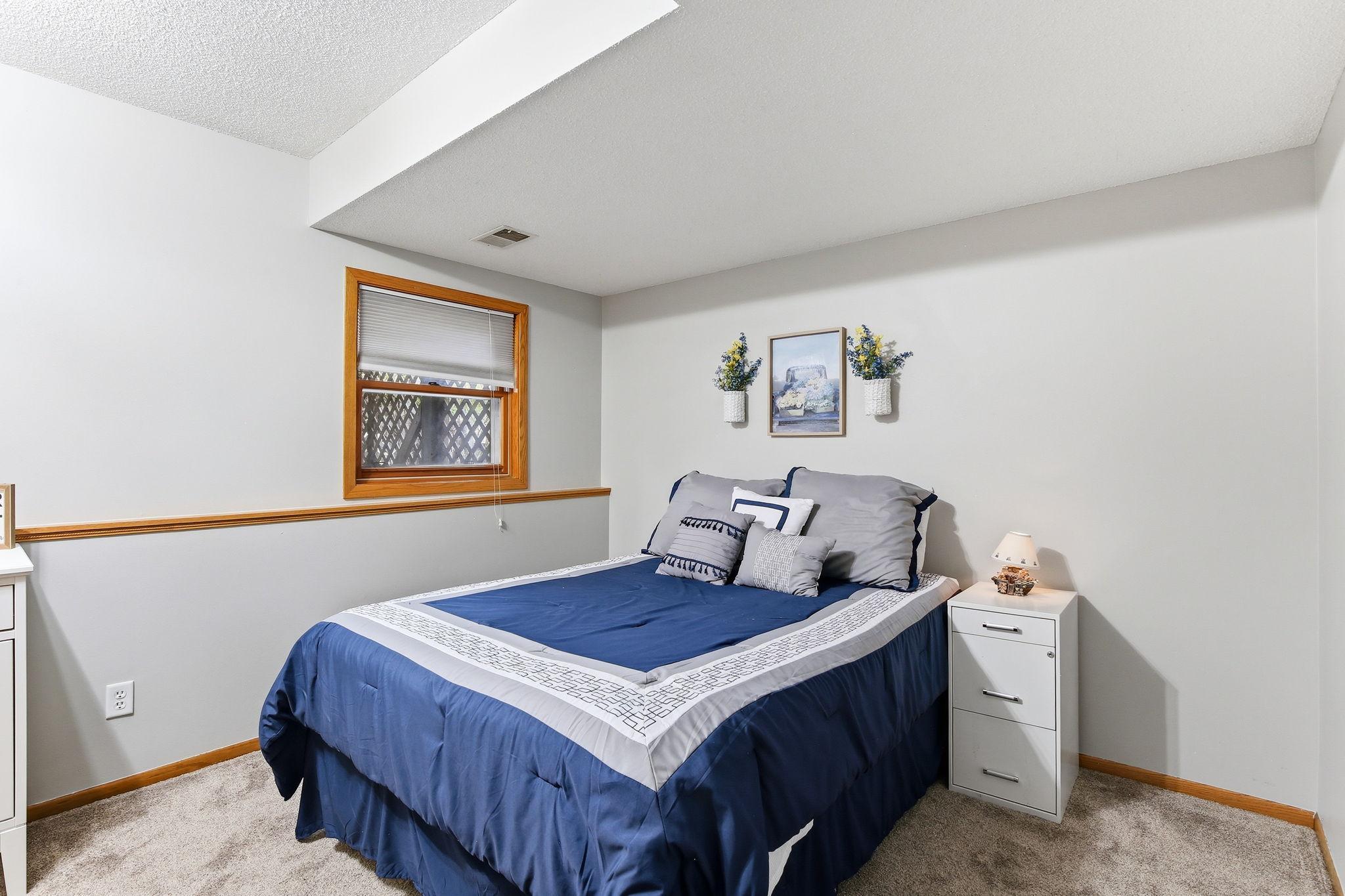 First of two lower-level bedrooms offering a comfortable and private space with a versatile layout, ideal for guests, a home office, or additional living needs.