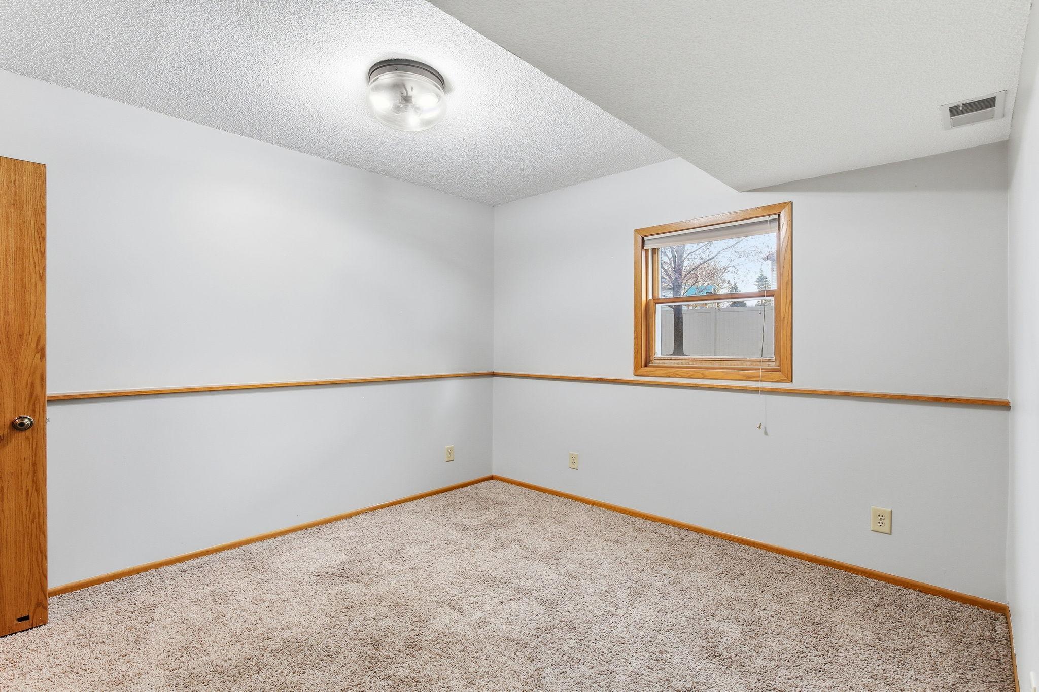 Second bedroom in the lower level offers a cozy and functional layout, perfect for guests, a home office, or flexible living space with comfortable proportions and natural versatility.