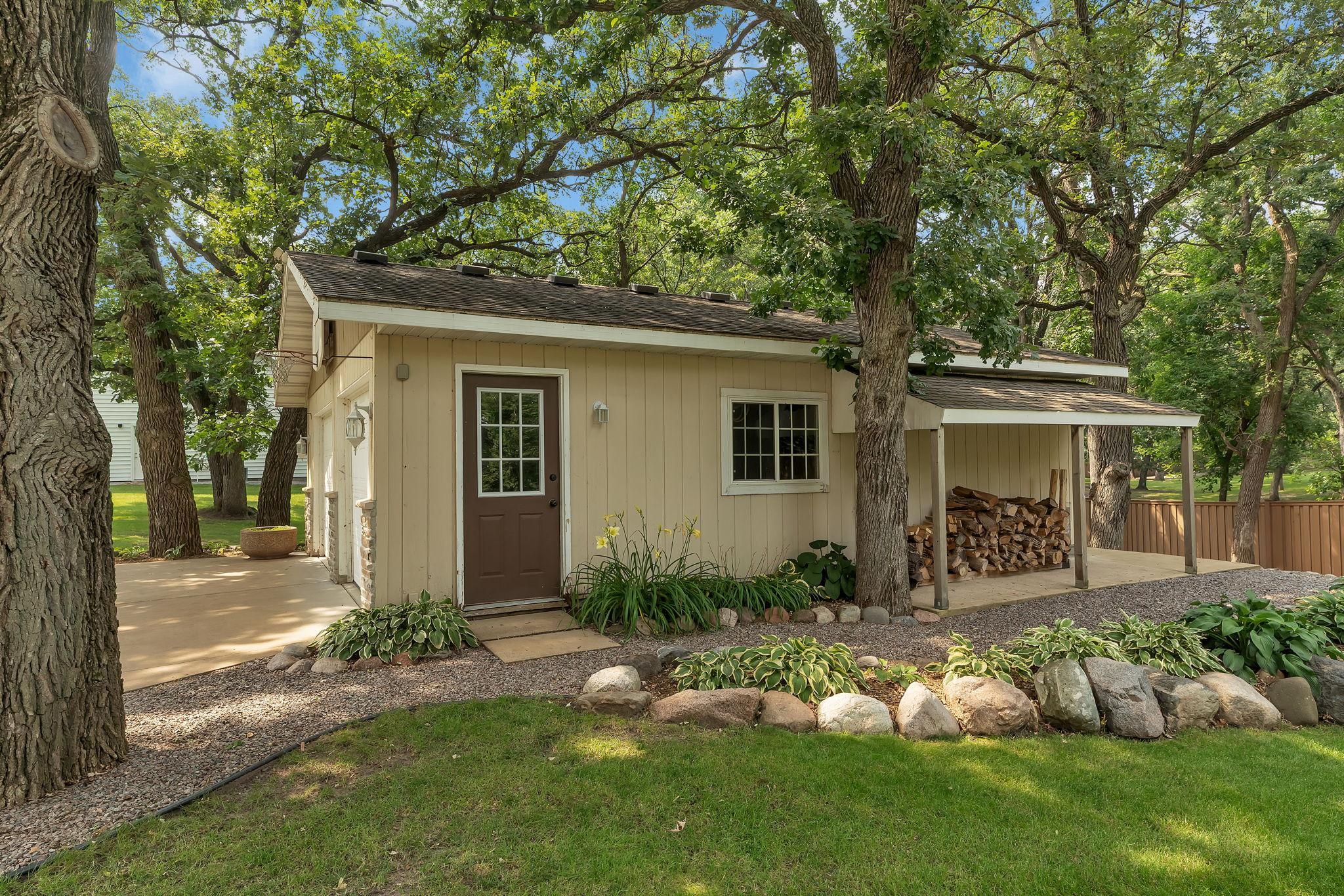 Enjoy the charm and serenity of an inviting porch, perfectly situated beneath a lush canopy of mature trees. Practical amenities include an additional two-car heated garage with generous storage.