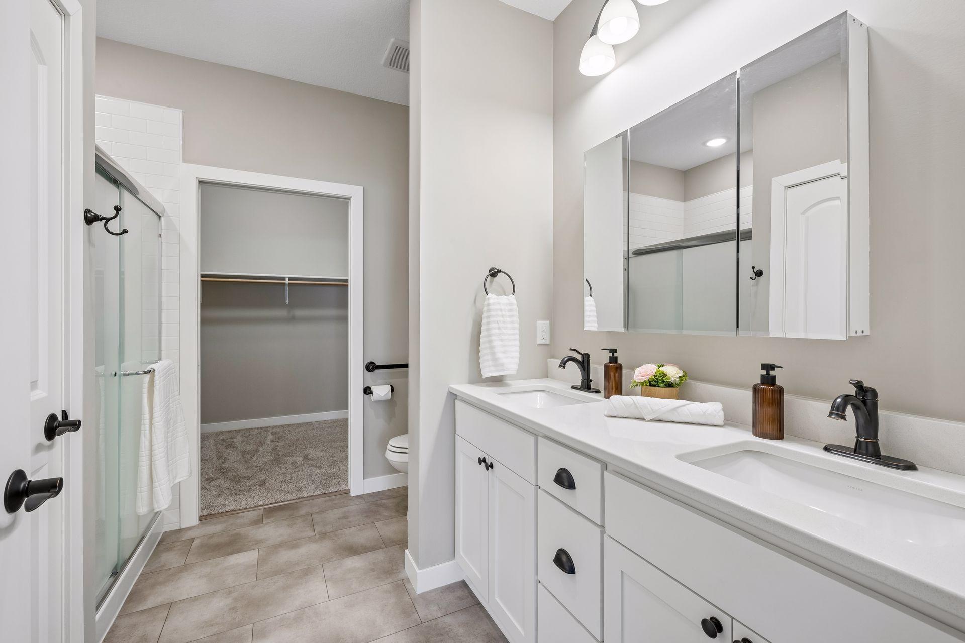 Primary ensuite with dual sink, custom cabinetry, quartz counters and walk-in shower.