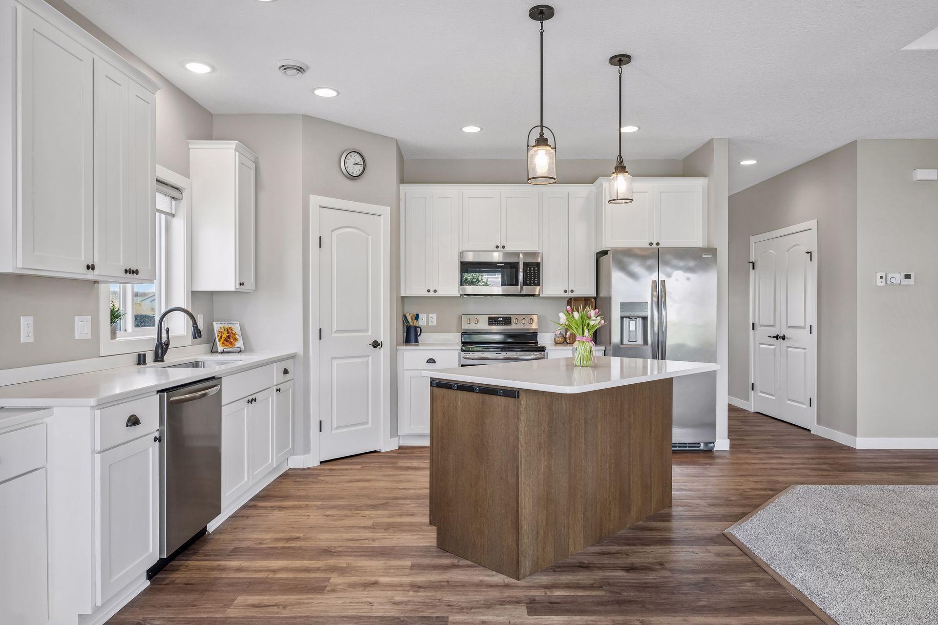 Beautiful white custom kitchen cabinets, quartz counters, kitchen island and stainless steel appliances.