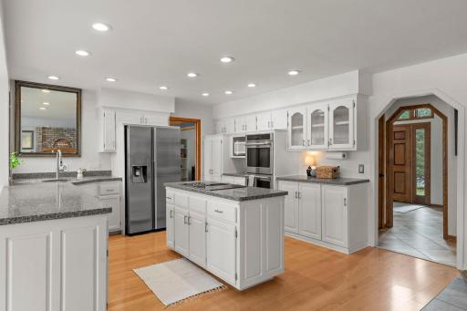 It features crisp white cabinetry and stainless steel appliances, including a double oven and downdraft cooktop, both less than six months old.