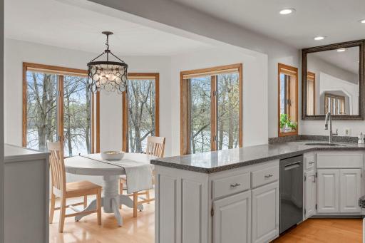 The adjacent informal dining area, set nearby a charming bay window, offers uninterrupted views of the lake.