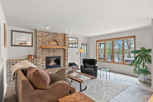 A warm and welcoming great room showcases a wood-burning fireplace with a classic brick surround and opens to the deck for effortless indoor-outdoor living.