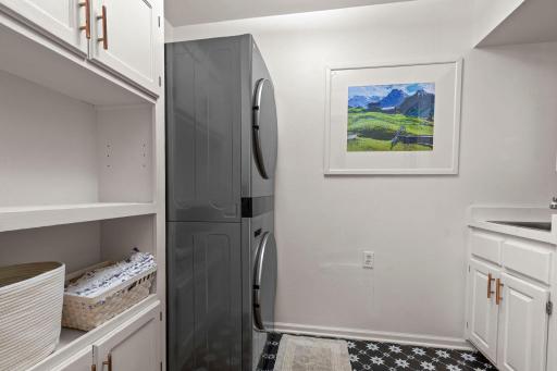 Well-equipped laundry room with storage, a utility sink, and nearly new washer and dryer, along with convenient access to the attached three-car garage.