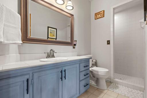 The adjacent bathroom with tile detailing and a spacious walk-in shower adds convenience, while abundant storage throughout the level enhances functionality and ease of everyday living.