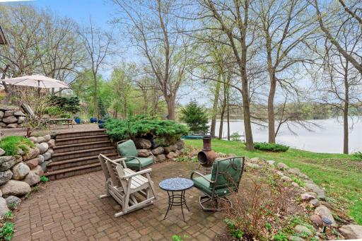 Mature trees and lush landscaping frame a two-tier paver patio.