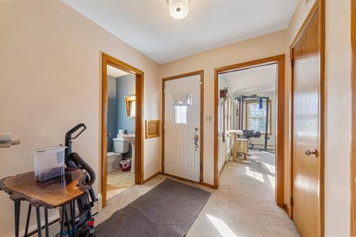 Hallway off kitchen that leads to half bath, outside, unfinished basement and living room