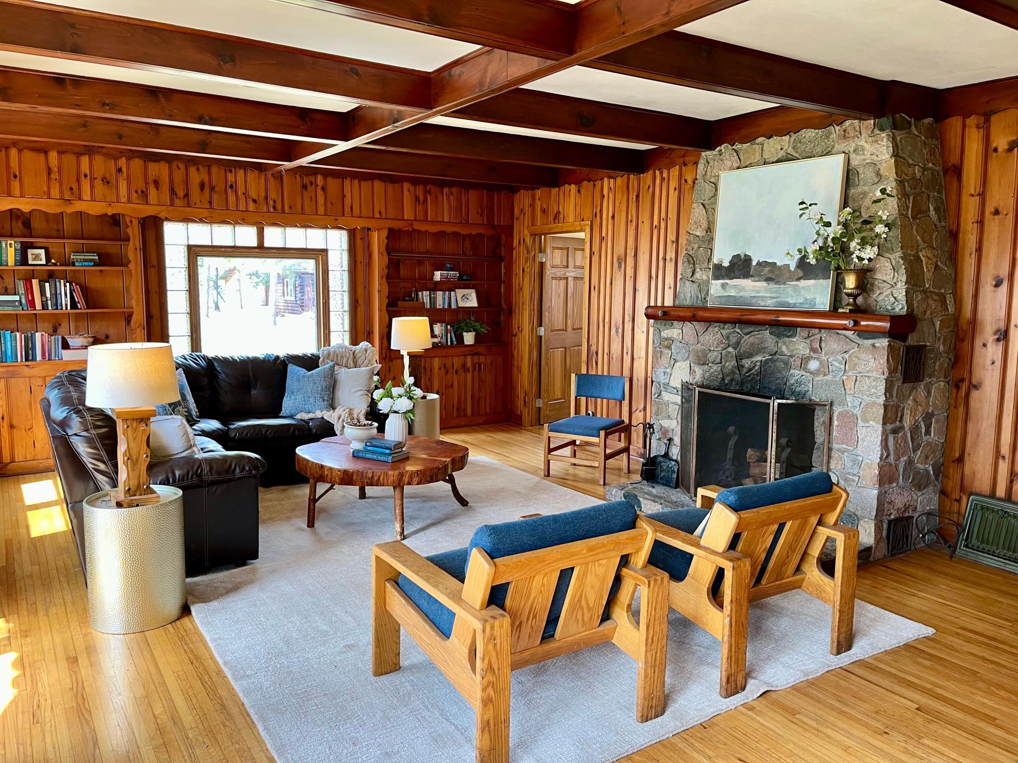 Living room with stone fireplace, original tongue and groove paneling , ceiling beams and wood flooring