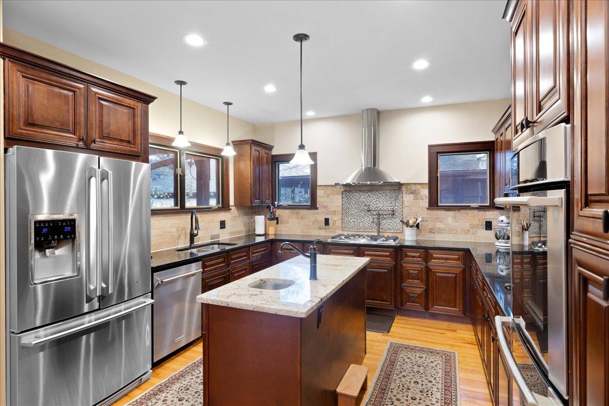 Beautifully updated kitchen featuring rich wood cabinetry, granite countertops, stainless steel appliances, and a center island with prep sink, designed for both everyday living and effortless entertaining.
