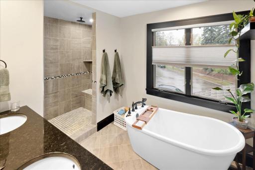 Spa-like bath featuring double vanity, soaking tub, and walk-in tiled shower, designed for comfort and functionality.