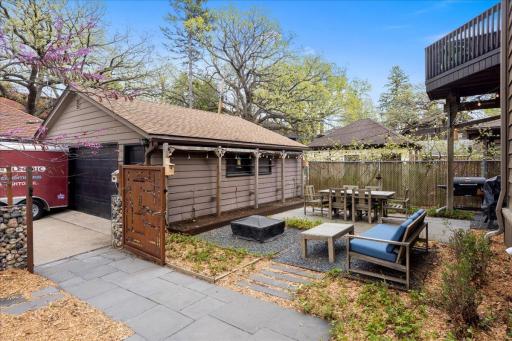 Fully enclosed backyard patio with custom gate and stone accents, includes multiple seating areas, dining space, and string lighting. Fully landscaped, easy to maintain and no grass to mow!