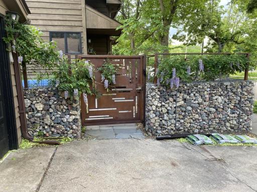 Private backyard entry featuring custom steel gate and stone accents, adding both security and architectural character.