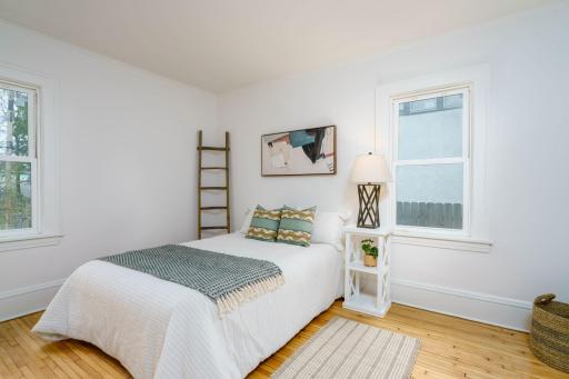 One of two bright and airy main-level bedrooms featuring fresh paint, gleaming hardwood floors with windows on two sides for abundant natural light.