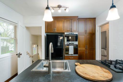 The kitchen blends new and old elements, featuring a cooktop, microwave and built-in oven, concrete countertops, and attractive cabinetry.