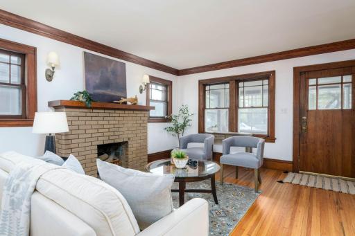 The living room boasts a charming decorative brick fireplace (per previous owners, it is not operational), flanked by two windows, crown molding and beautifully refinished hardwood floors.