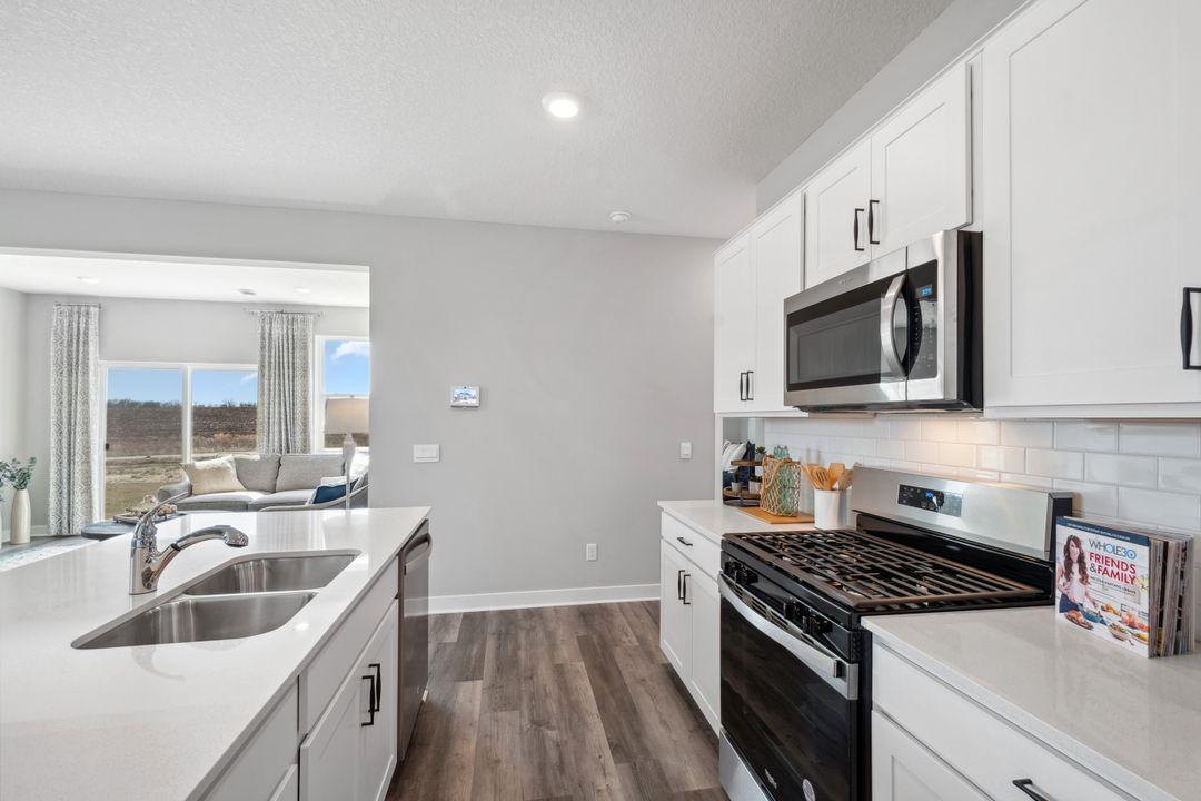 Expansive kitchen with backsplash and stainless steel appliances. *Photo is of a past model home, finishes, selections, layout to vary.