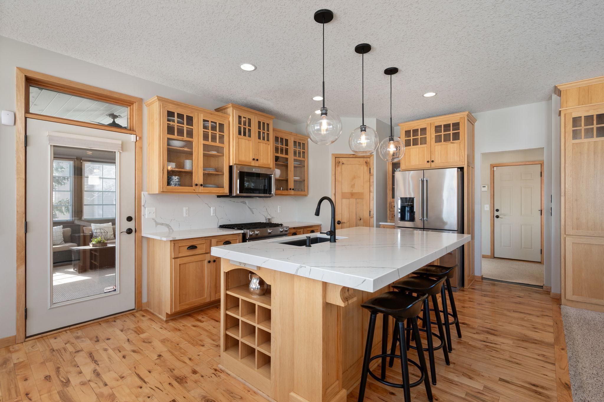 Hickory cabinets with glass fronts and thick quartz countertops and backsplash