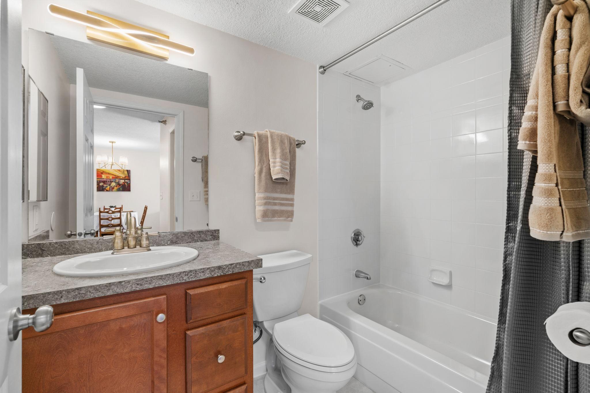Bathroom with new comfort height elongated toilet, new brushed metal light fixture, glazed shower and tub