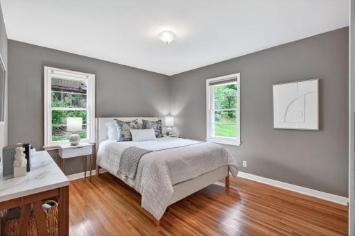 Spacious main-level bedroom with hardwood floors and calming natural light