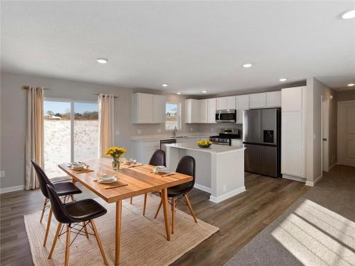 Dining Room and Kitchen. Virtually Staged. Photo taken of another home with similar plan and finishes. Photos and renderings may not depict actual plan, materials, & finishes may vary. All measurements are approximate.