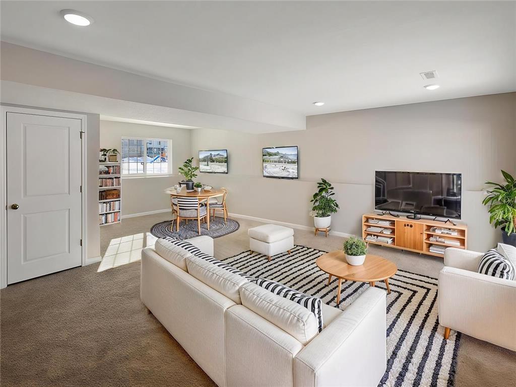 Finished Lower Level Family Room, Virtually Staged. Photo taken of another home with similar plan and finishes. Photos and renderings may not depict actual plan, materials, & finishes may vary. All measurements are approximate.