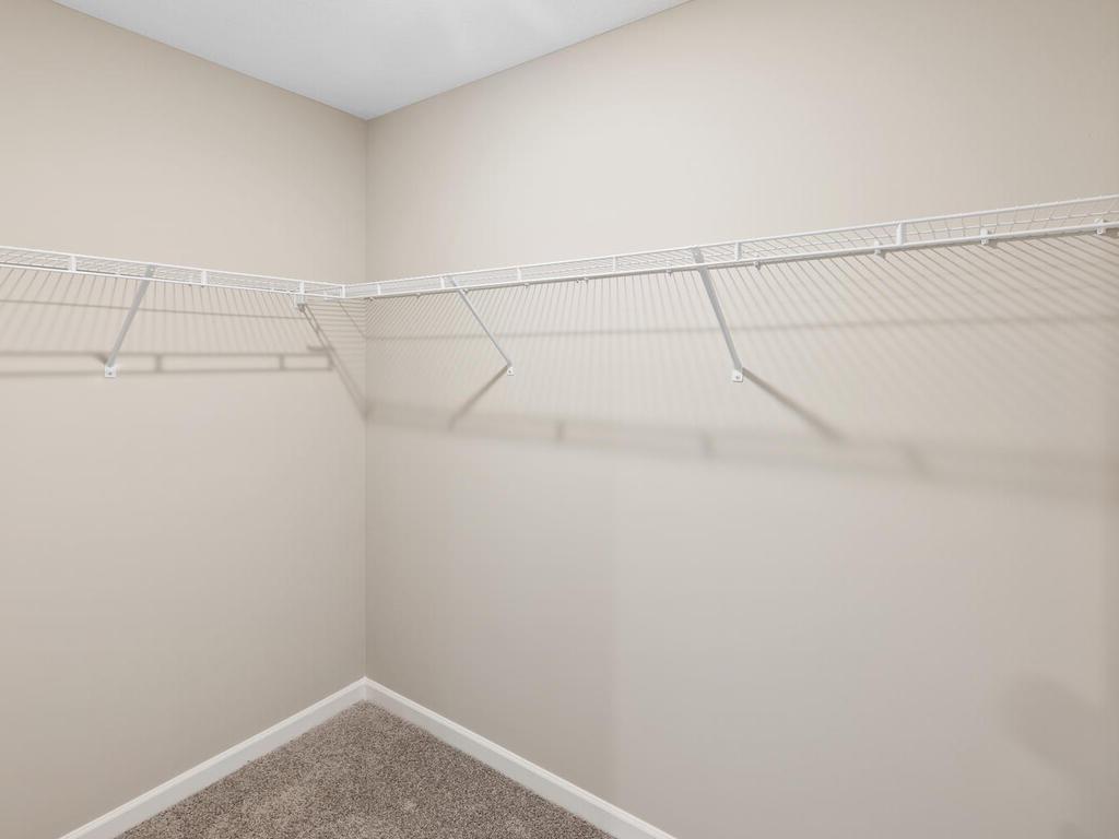 Primary Bedroom Walk In Closet. Photo taken of another home with similar plan and finishes. Photos and renderings may not depict actual plan, materials, & finishes may vary. All measurements are approximate.