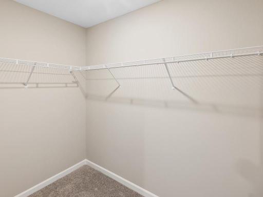 Primary Bedroom Walk In Closet. Photo taken of another home with similar plan and finishes. Photos and renderings may not depict actual plan, materials, & finishes may vary. All measurements are approximate.