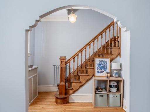 Unique architectural archways, hardwood floors, and original wood staircase detailing add timeless character throughout the home.