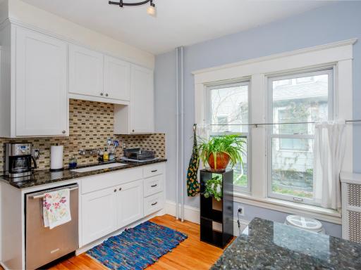 Updated bright and open kitchen featuring granite countertops and a tile backsplash.